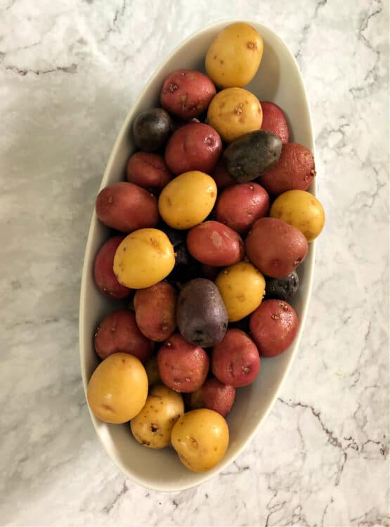 raw tri-color potatoes in a white oval bowl