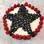 top view of decorated patriotic torte with large star made of blueberries surrounded by a circle of raspberries
