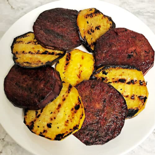 slices of grilled red and golden beets in an overlapping circle on a plate