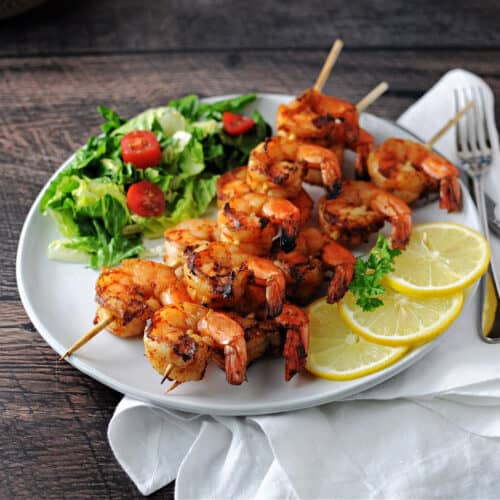 Grilled Cajun Shrimp on a plate with a small green salad and some lemon slices