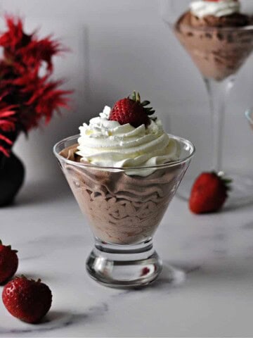 Easy chocolate mousse in a stemless martini glass topped with whipped cream and a strawberry