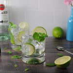 Bacardi mojito in a glass with ice, mint and limes. a second mojito is behind the first.