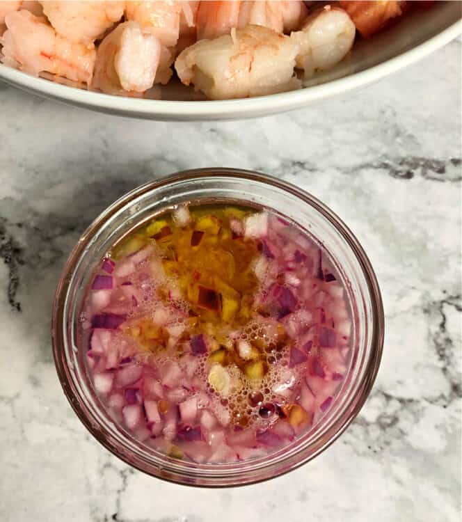 chopped red onion in a small cup with a marinade