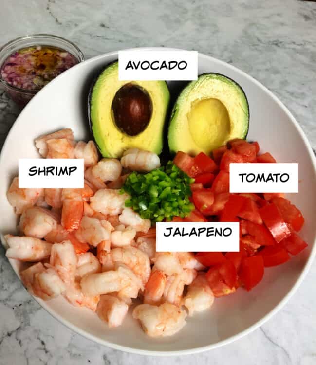 ingredeints in a bowl: cooked shrimp, avocado, tomato, chopped jalapeno