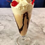 Kahlua mudslide ice cream drink in a tall glass topped with whipped cream and a cherry