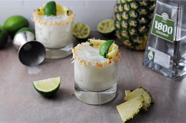 top down view of drinks with squeezed limes and pineapple slices around