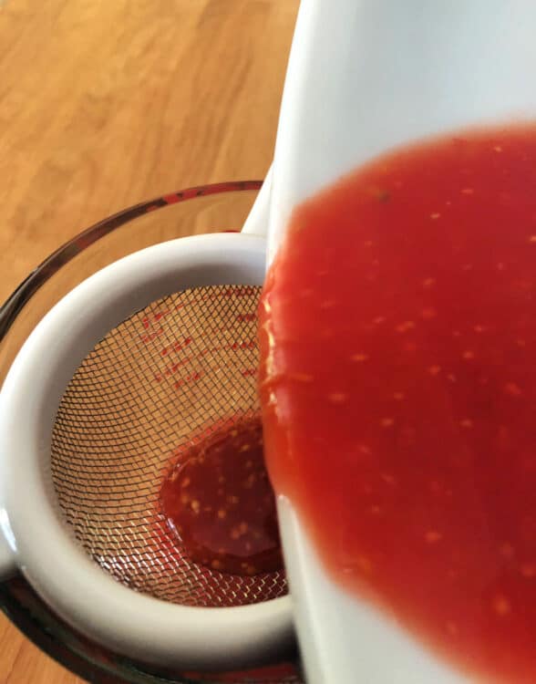 tomato juice pouring througha sieve to strain out the seeds