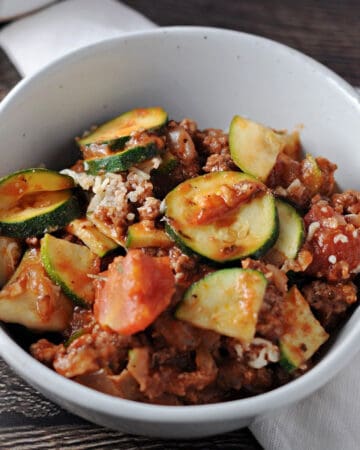 zucchini ground beef casserole in a small white bowl sitting on a white napkin