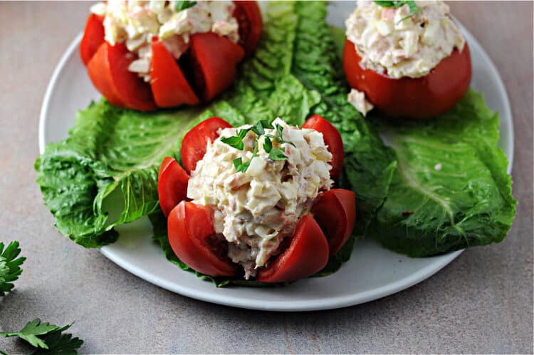 tuna stuffed tomato on a plate with 2 others behind it