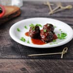 grape jelly bbq meatballs on a small white plate