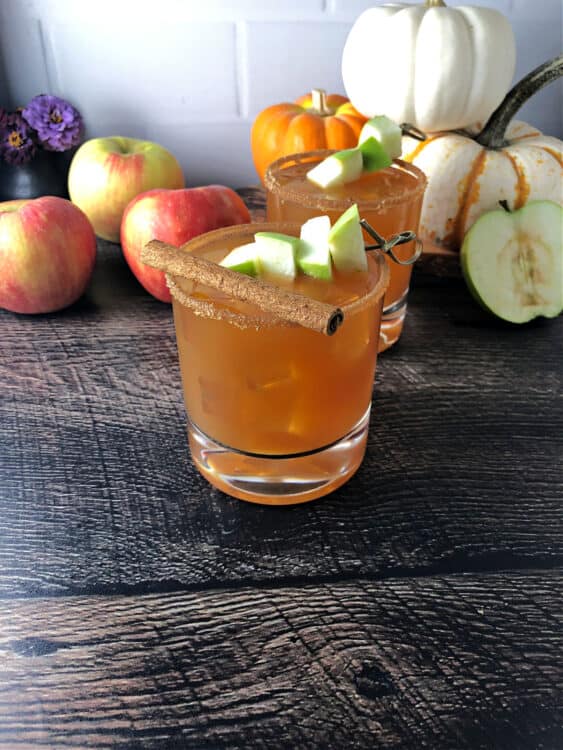 caramel apple cider vodka cocktail garnished with apple cubes and a cinnamon stick