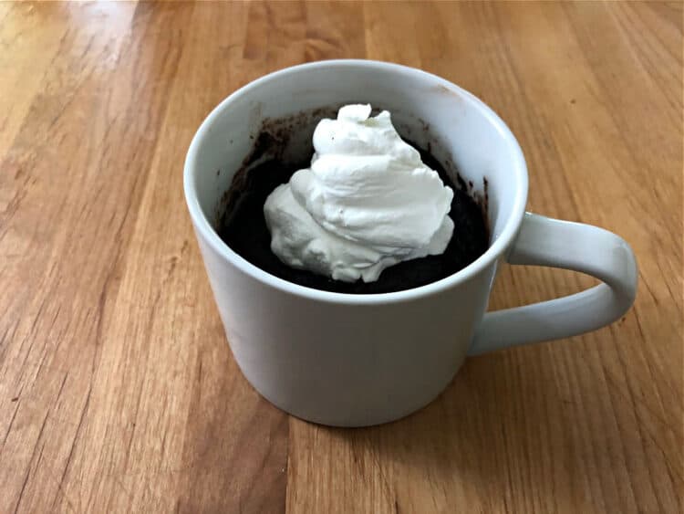 Keto chocolate cake in a mug with whipped cream on top