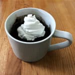 Keto chocolate mug cake topped with whipped cream, all in a white mug