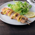 salmon kabob served on a plate with a green salad