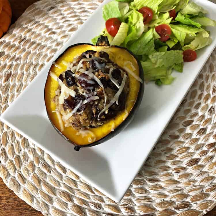 stuffed acorn squash on a white rectangular platter with a green salad