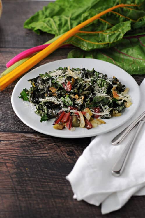 roasted swiss chard on a small white plate with some raw pieces behind