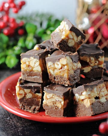 Snickers fudge piled on a small red plate, surrounded by holiday decor