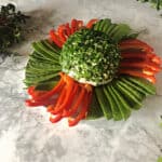 green onion cheese ball surrpunded by red and green vegetables