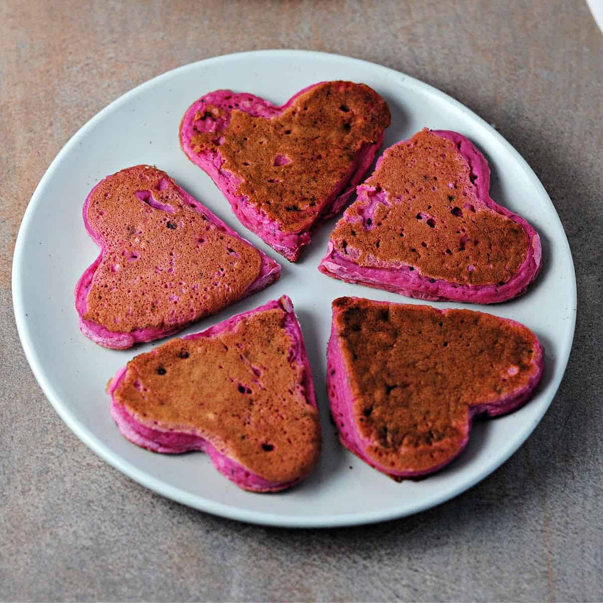 5 heart shaped dragon fruit pancakes on a small plate