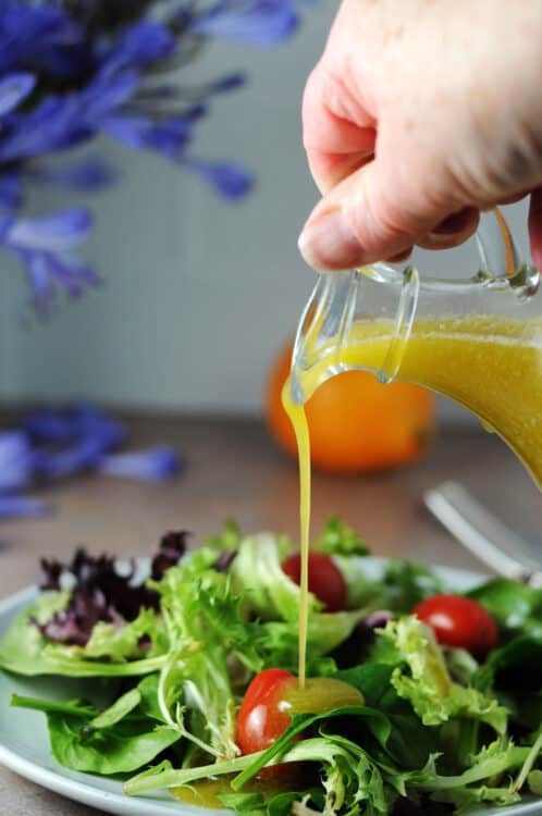 meyer lemon vinaigrette pouring onto a small salad