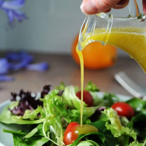 meyer lemon vinaigrette salad dressing pouring onto a salad