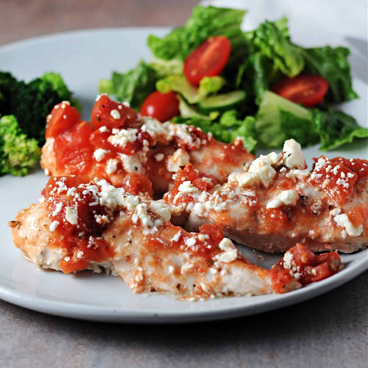 healthy baked feta chicken tenderloins on a plate with salad.