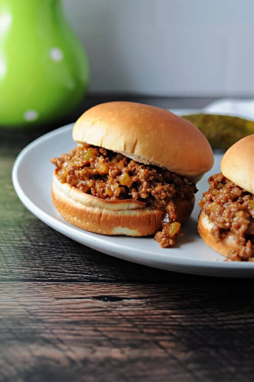 2 sloppy joes on buns, served on a white plate.