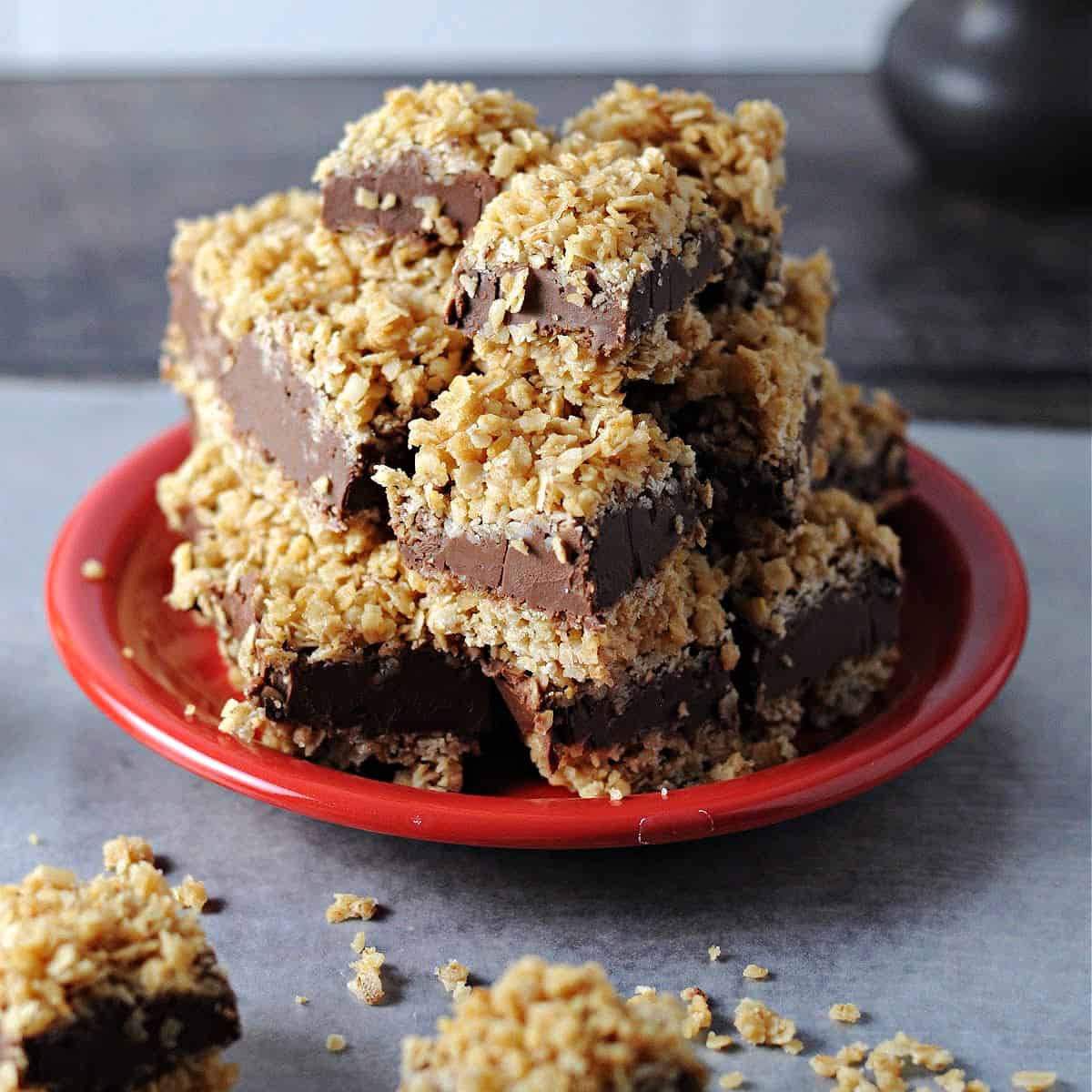 red plate with a stack of chocolate peanut butter oatmeal bars