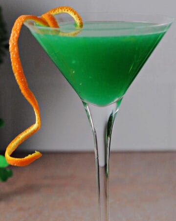 shamrock martini cocktail, bright green color with an orange rind garnish.