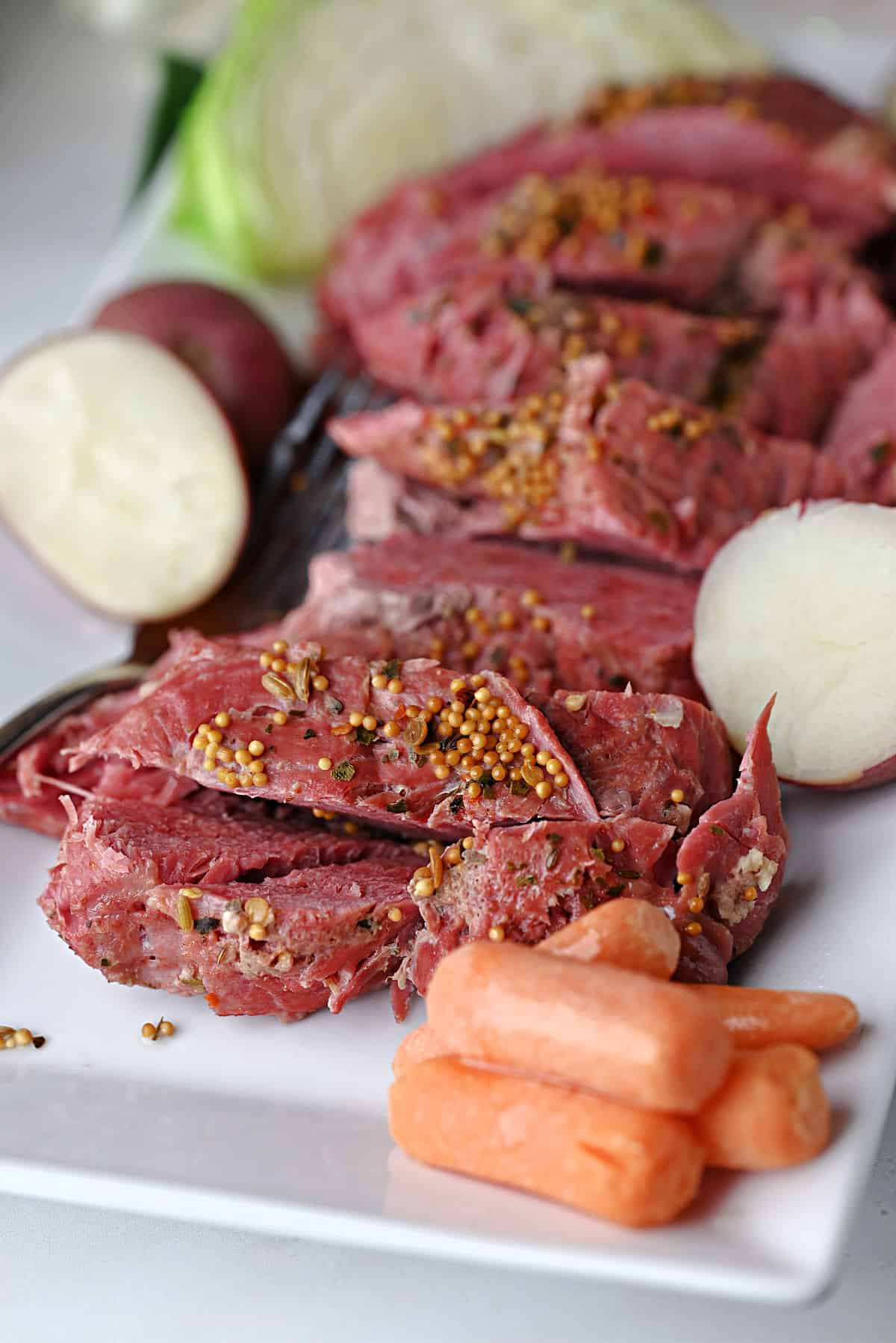 Instant Pot Corned beef sliced on a platter with veggies.