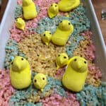 pan of peeps rice krispie treats decorated with whole peeps and some extra heads of peeps.