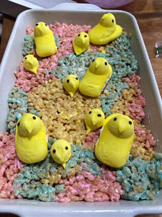 pan of peeps rice krispie treats decorated with whole peeps and some extra heads of peeps.