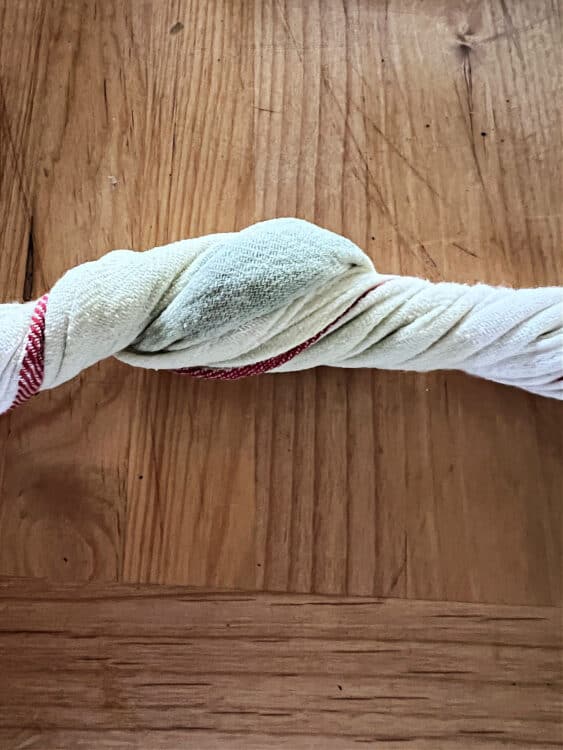 towel being used to squeeze moisture from spinach.
