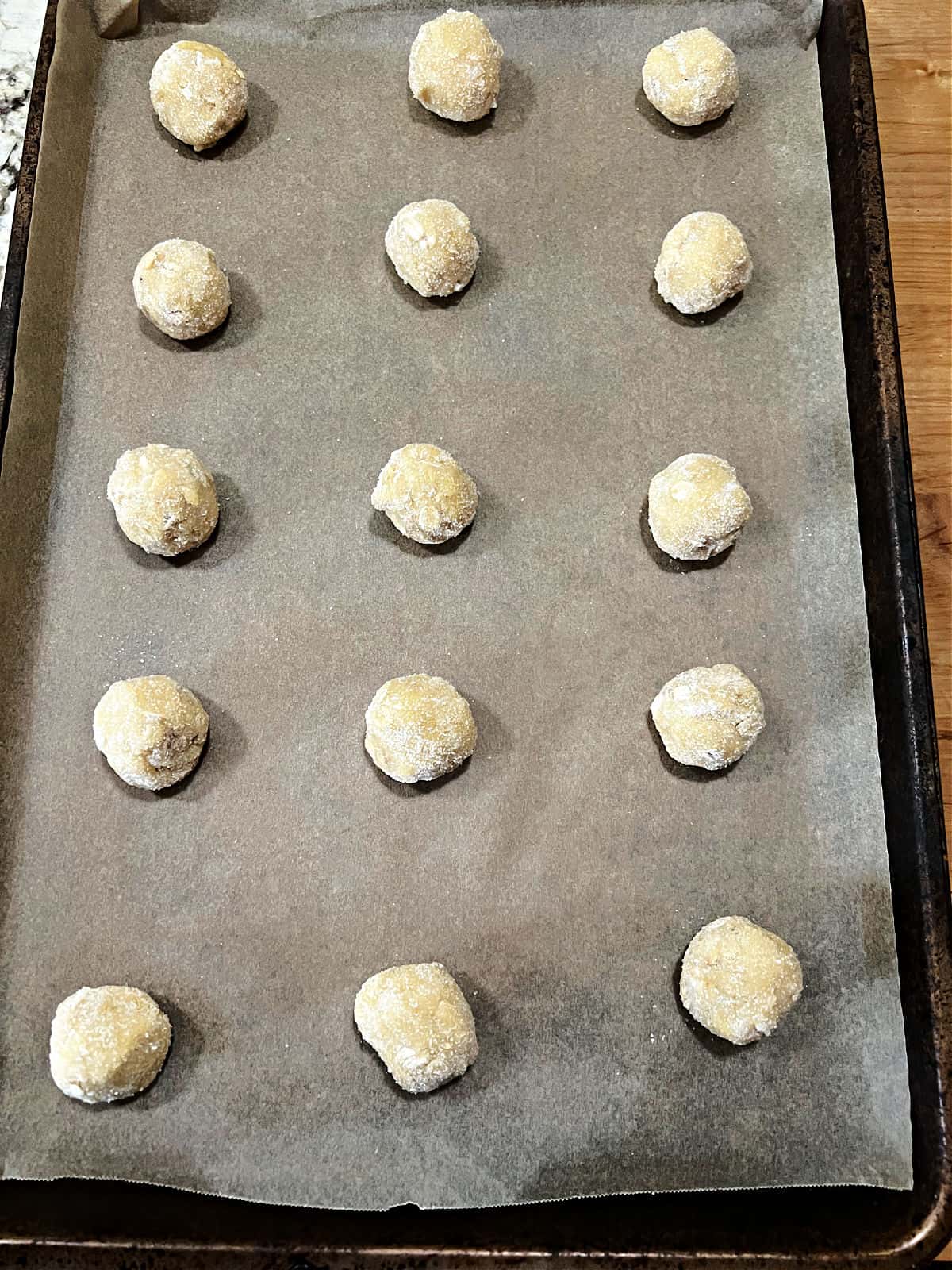balls of dough lined up on a baking sheet.