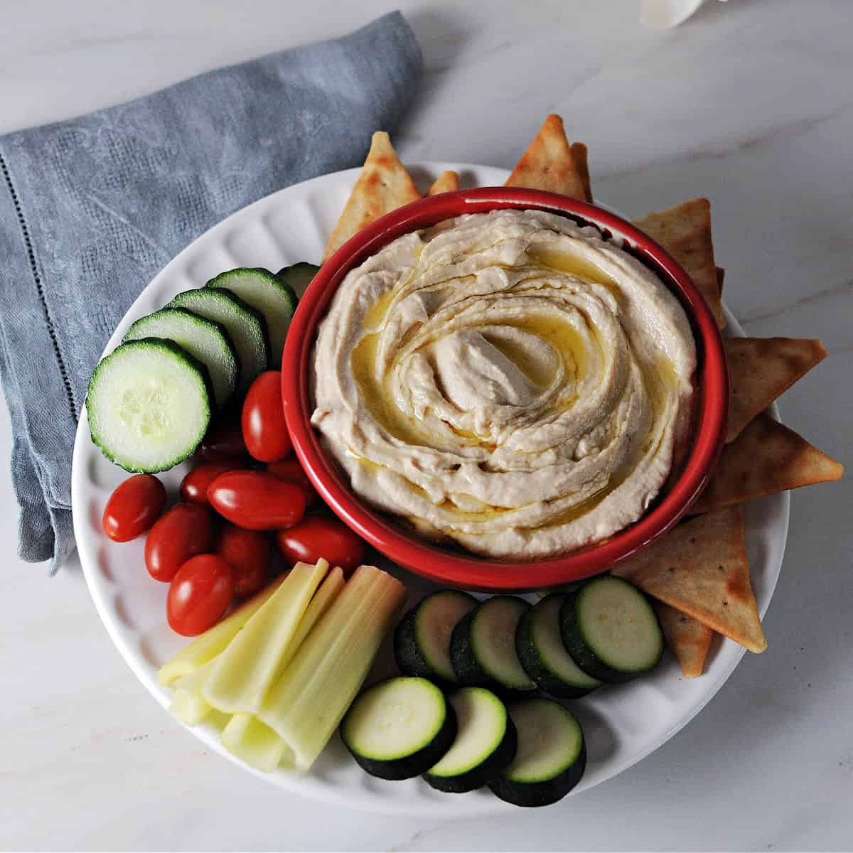 bowl of buuter bean hummus surrounded by crackers and veggies.