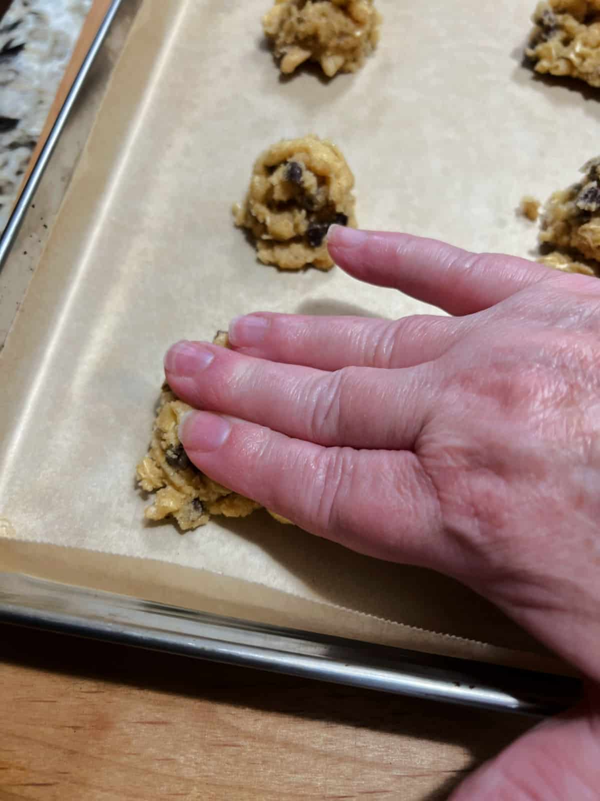flattening the ball of dough slightly on the baking sheet.