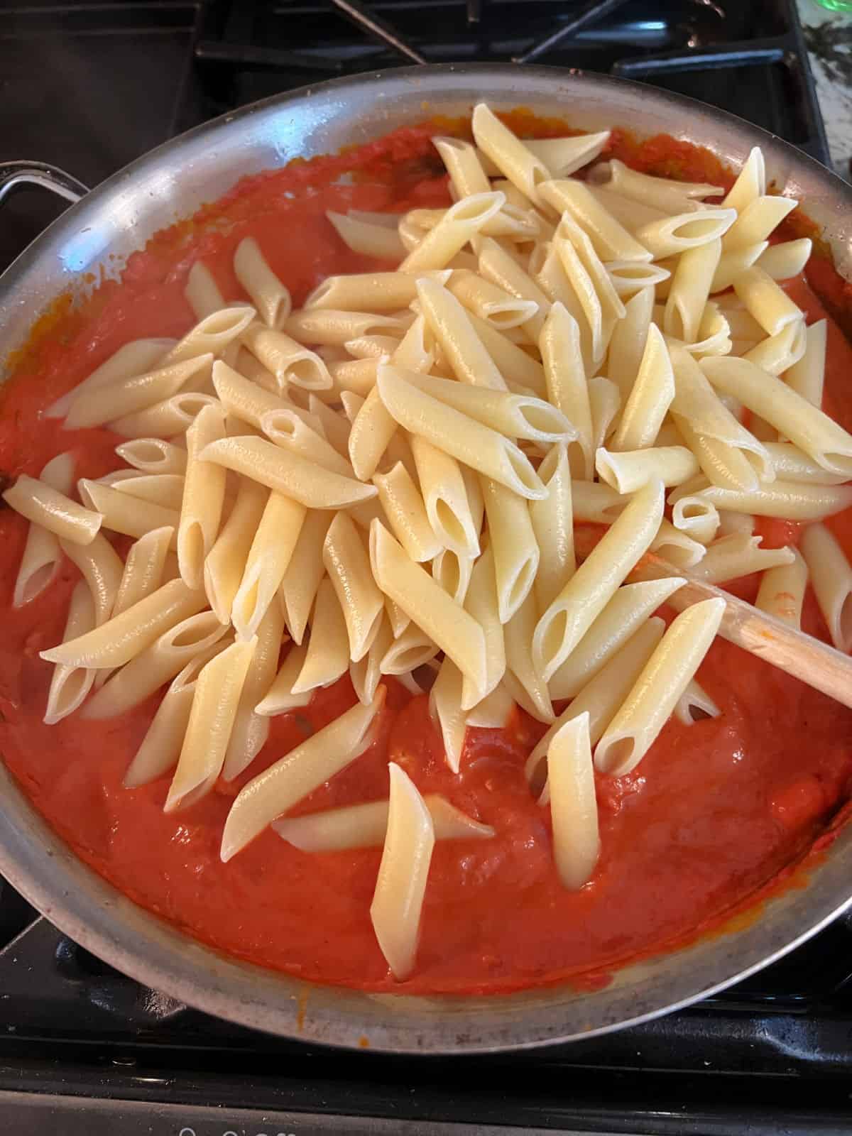penne pasta added to the skillet of vodka sauce.