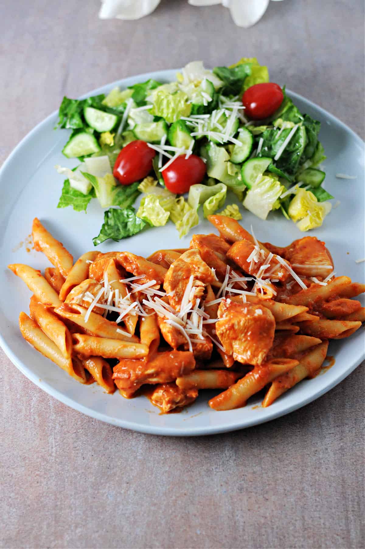 plate of penne alla vodka with chicken, served with a salad.