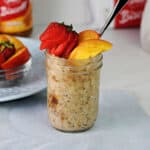 Biscoff overnight oats in a jar garnished with slices of nectarine and a strawberry.