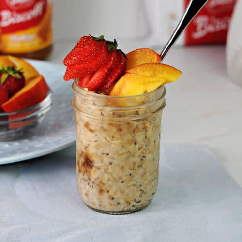 Biscoff overnight oats in a jar garnished with slices of nectarine and a strawberry.