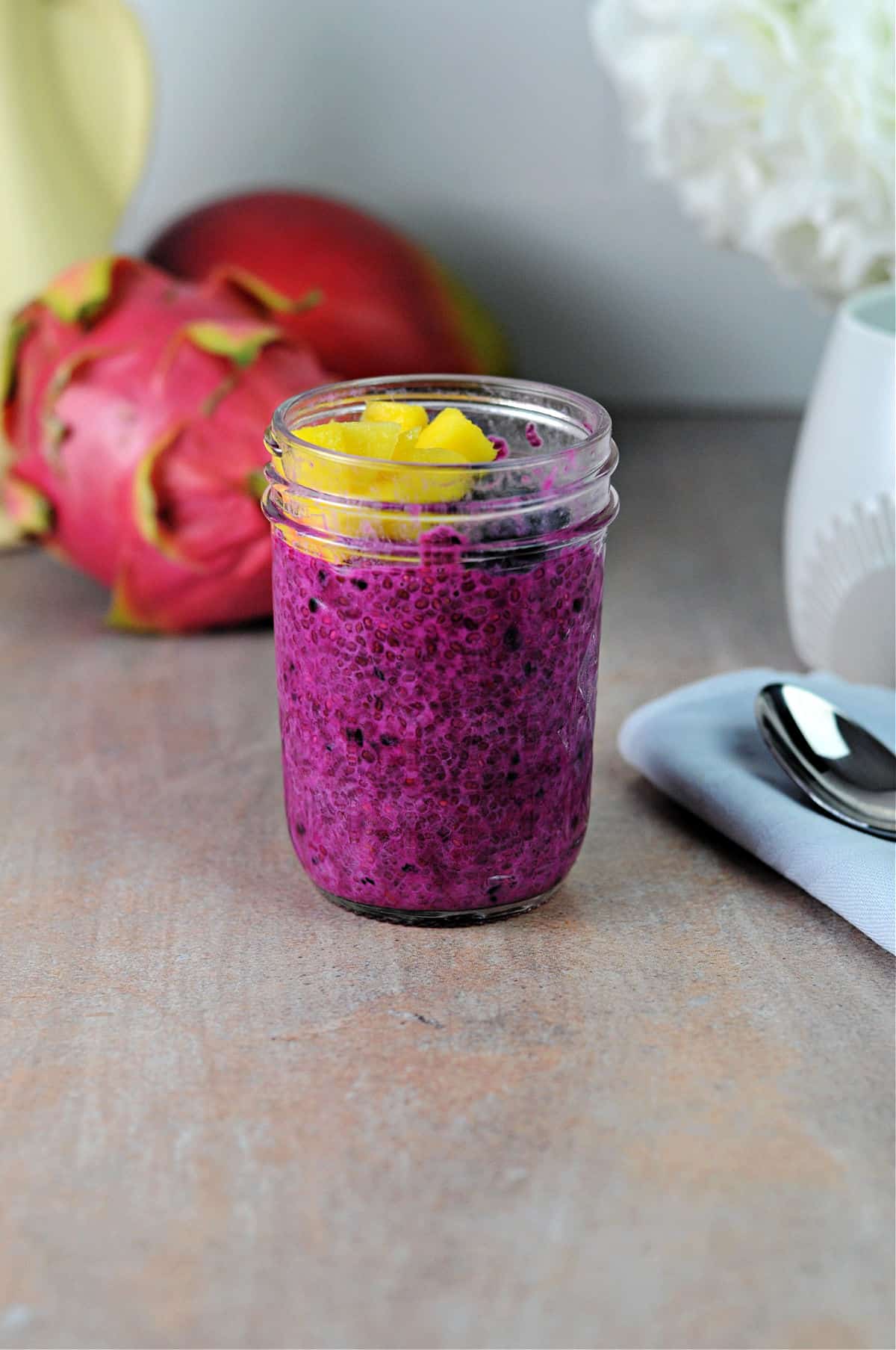 jar of pink chia pudding topped with fruit and ready to eat.