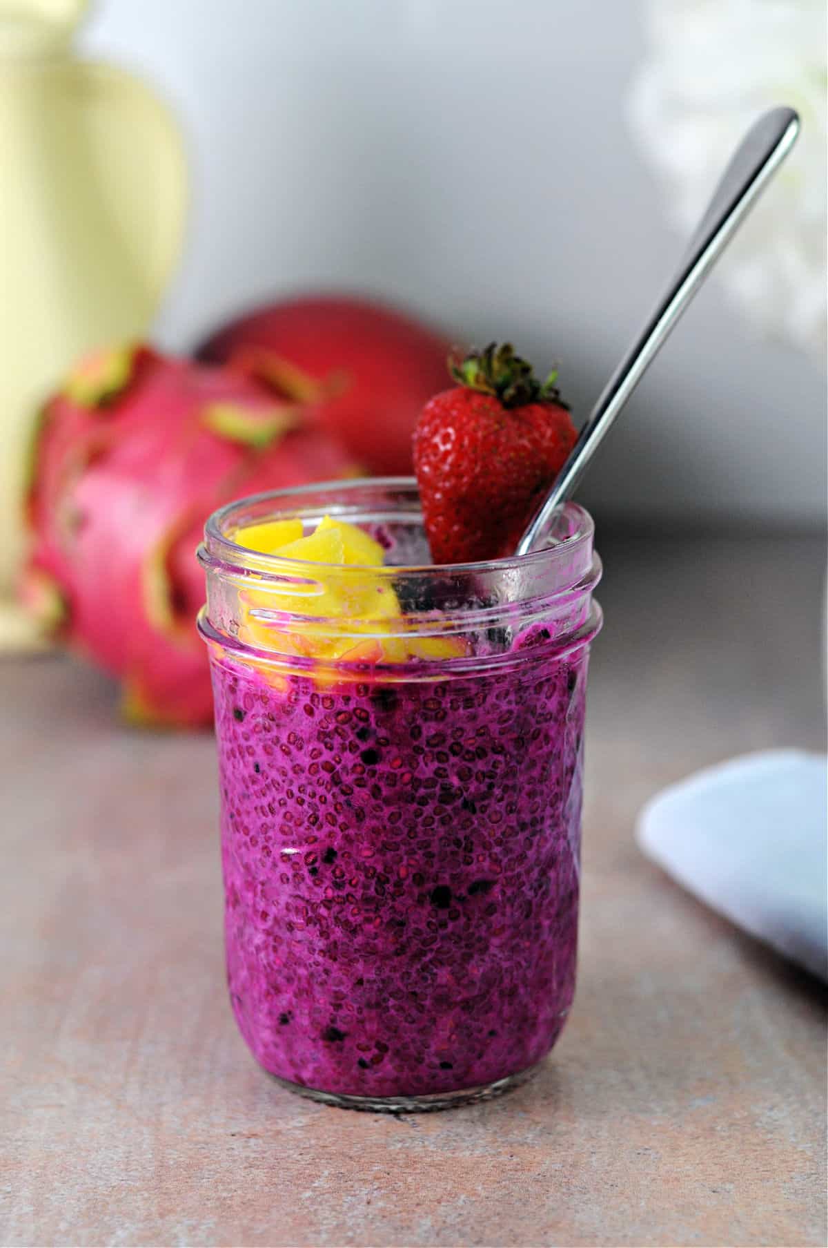 small jar of dragon fruit chia seed pudding garnished with fruit.