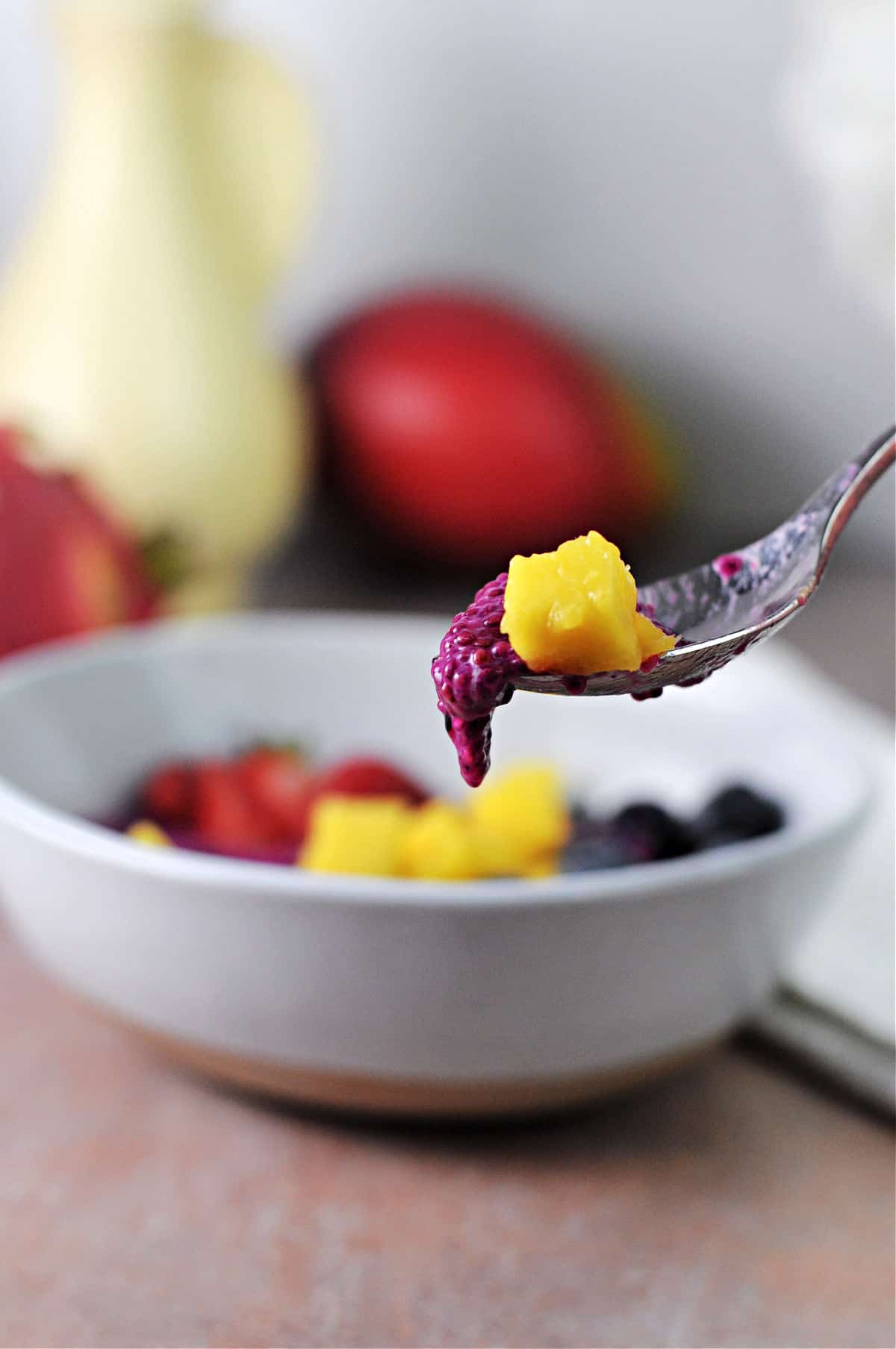 spoon holding fruit and chia seed pudding.