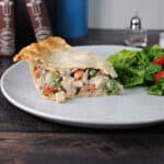 slice of chicken or turkey pot pie on a plate with some salad.