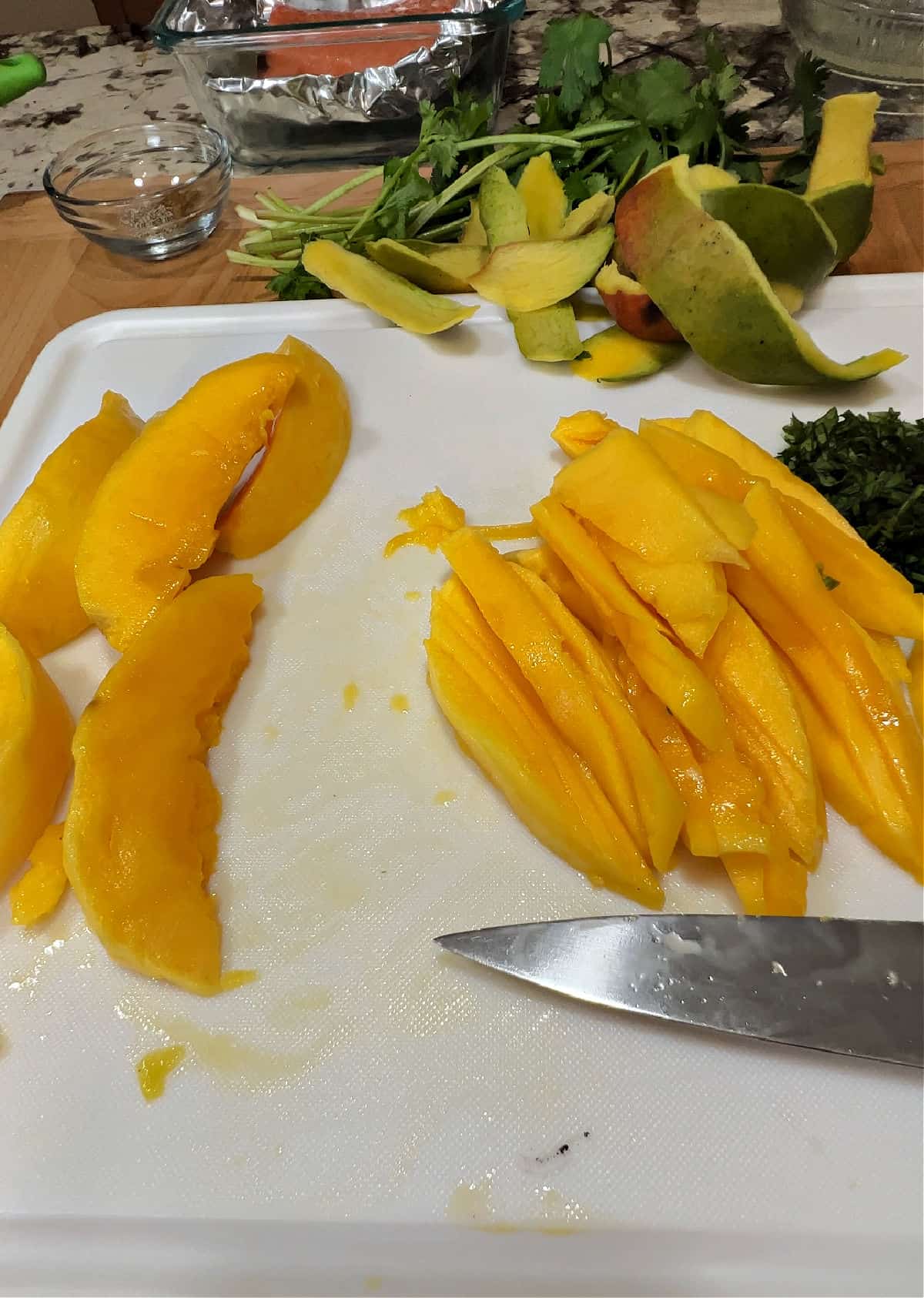 strips of cut up mango on a white cutting board.