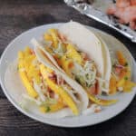 3soft shell fish tacos with mango slaw on top.