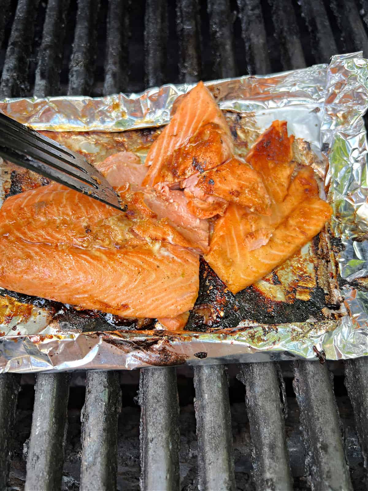 spatula pushing on cooked salmon, causing it to flake apart.