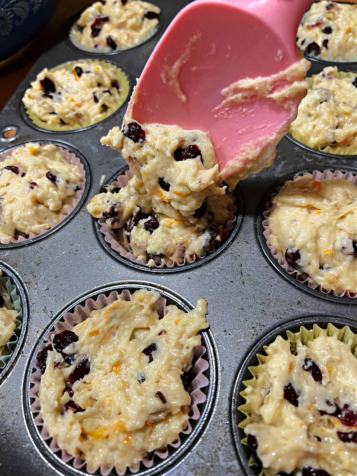 spatula dropping batter into muffin cups.