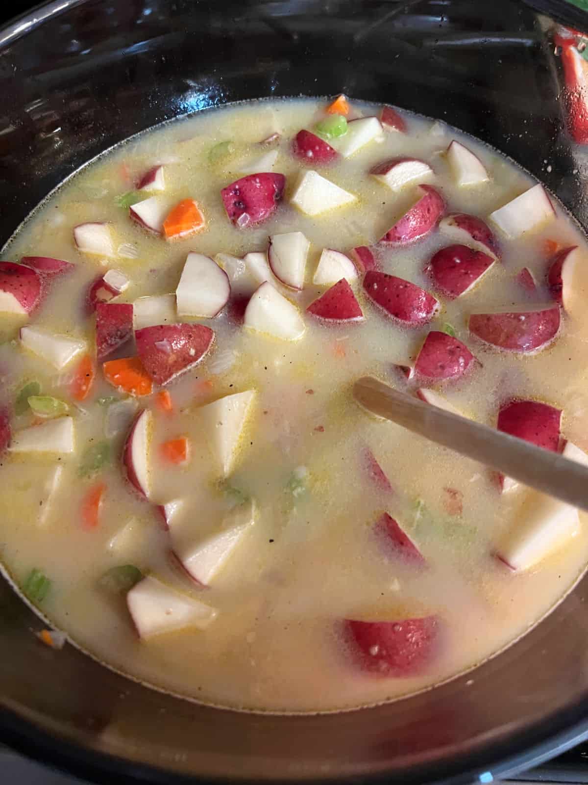 potatoes and vegetables with liquids in the soup pot.