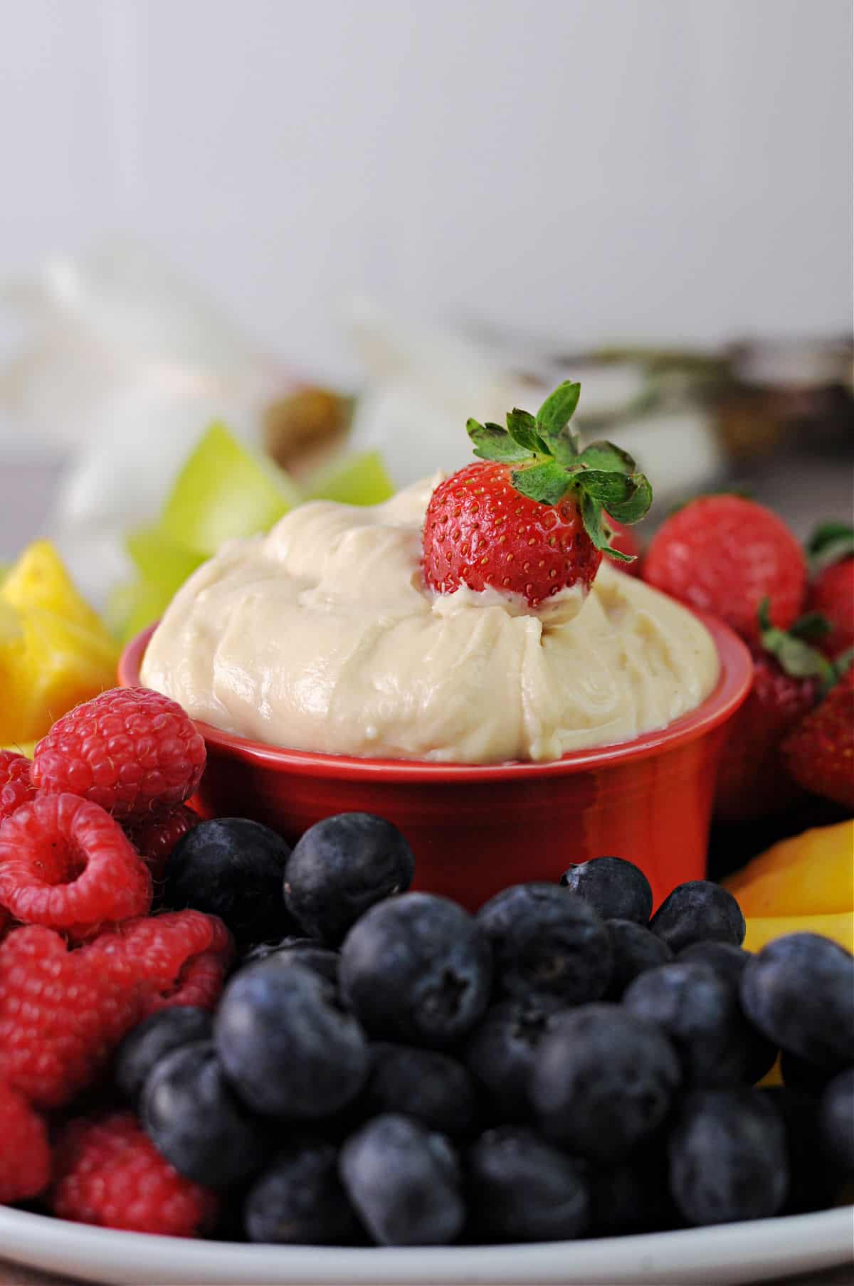 Cream cheese fruit dip surrounded by a platter of fruit.